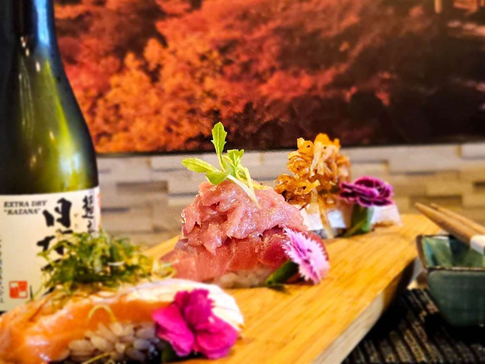 Chef's selection of seasonal nigiri plated beside a bottle of sake