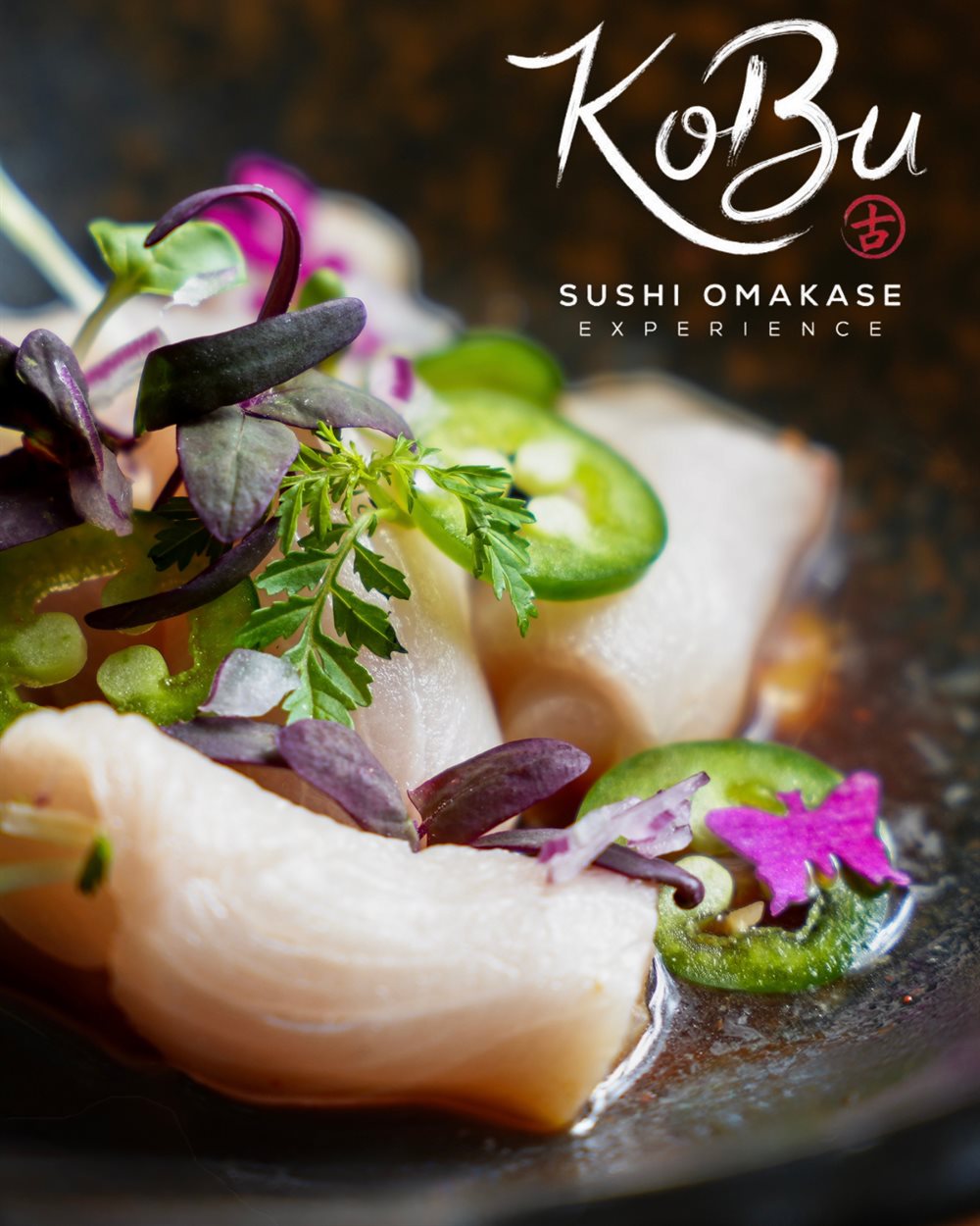 Slices of hamachi dressed with jalapeño, micro greens and an edible flower in a dark bowl